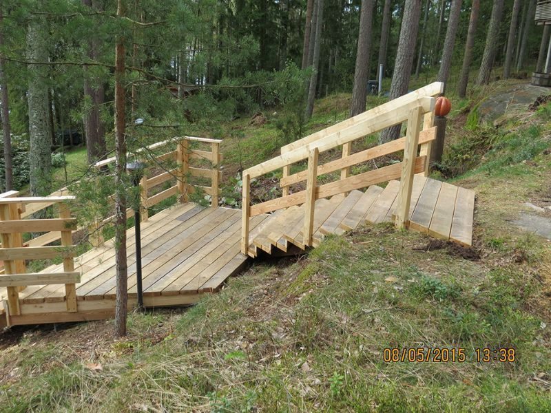 Puinen ulkosilta kaiteineen metsässä